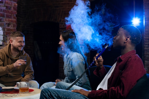 Young people vaping from a hookah in a bar