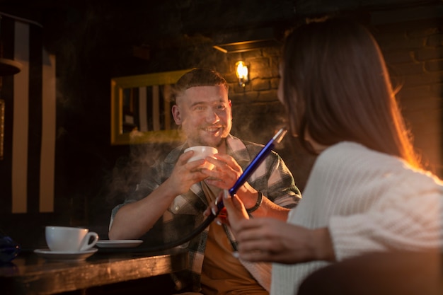 Free Photo young people vaping from a hookah in a bar