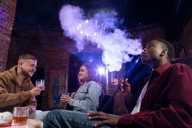 Young people vaping from a hookah in a bar