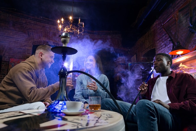 Young people vaping from a hookah in a bar