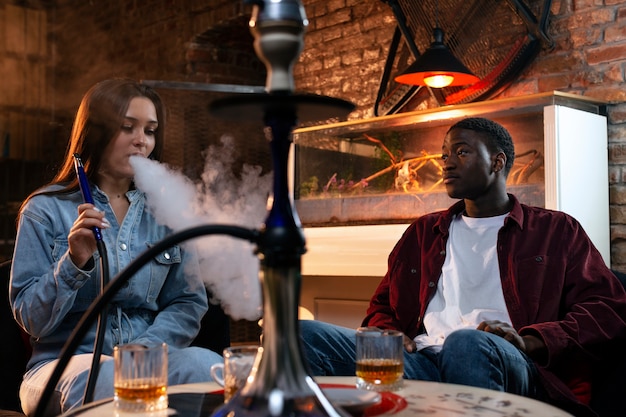 Young people vaping from a hookah in a bar