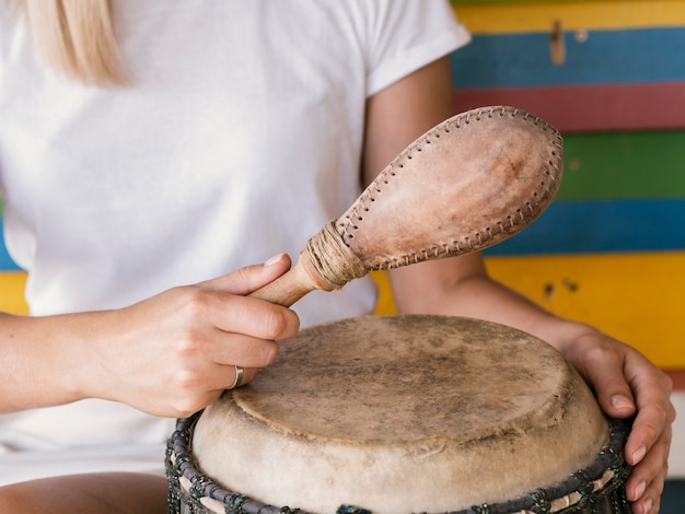 Young person playing percussion instruments near multicolored wall