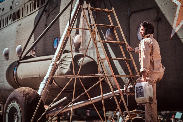 Young pilot makes a stop to refuel his cargo airplane using stairs. It's bright, sunny day.