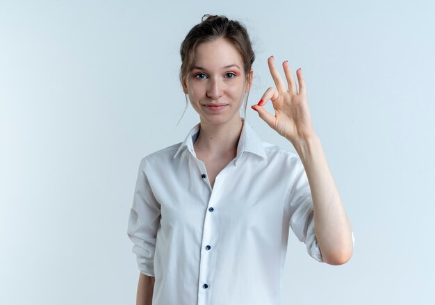 Young pleased blonde russian girl gestures ok hand sign isolated on white space with copy space