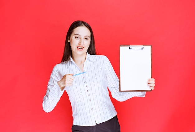 Free Photo young positive businesswoman holding empty clipboard and posing. 