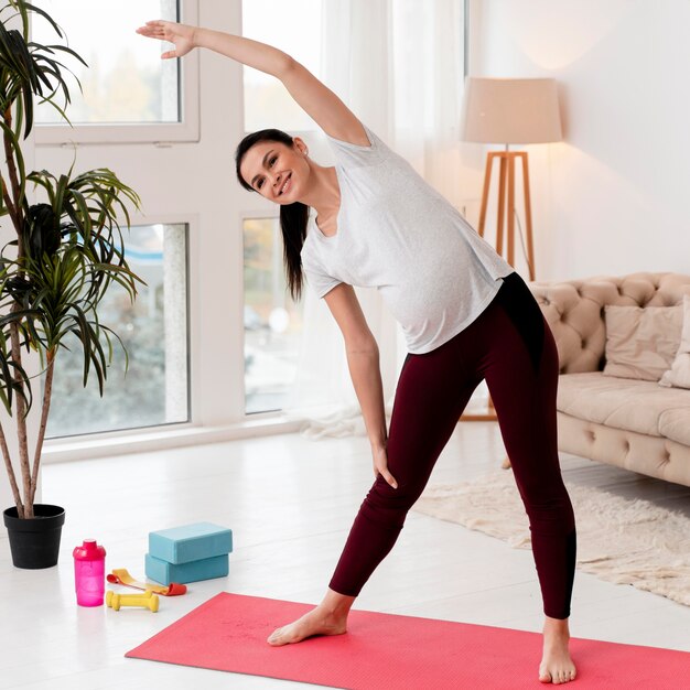 Young pregnant woman exercising on fitness mat