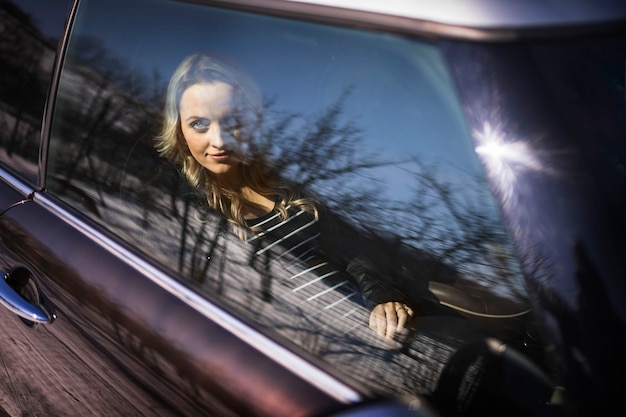 Free photo young pregnant woman looking through transparent car window