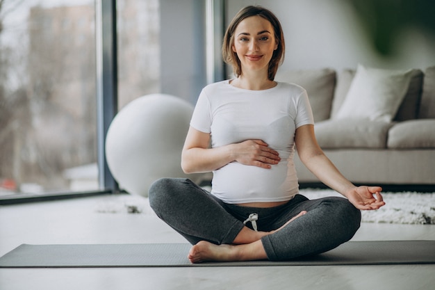 Free Photo young pregnant woman practicing yoga at home