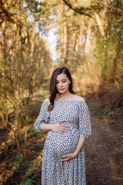 Young pregnant woman relaxing in park outdoors