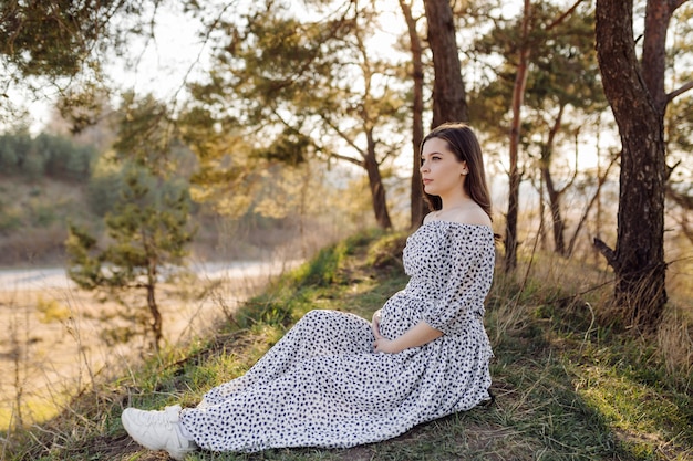 Young pregnant woman relaxing in park outdoors