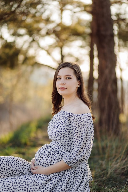 Young pregnant woman relaxing in park outdoors