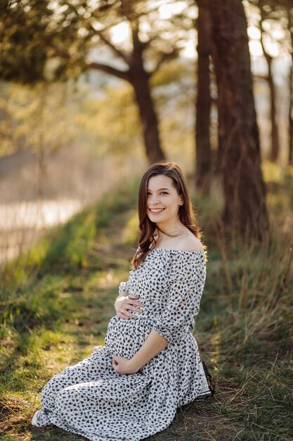 Young pregnant woman relaxing in park outdoors