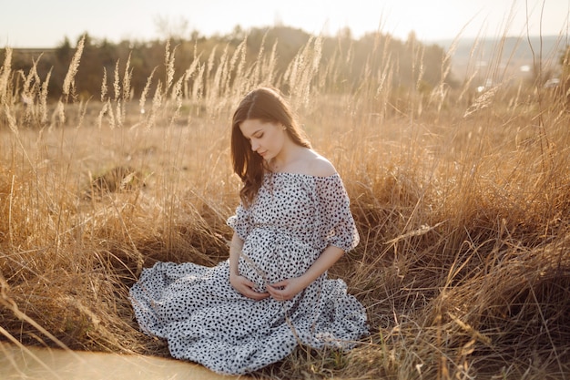 Young pregnant woman relaxing in park outdoors