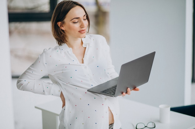 Young pregnant woman working on computer out of the office