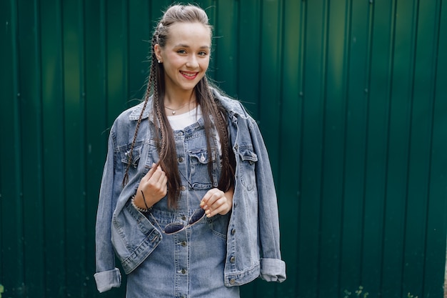 Free Photo young pretty attractive girl in denim clothes in glasses on a simple dark green background with empty place for text