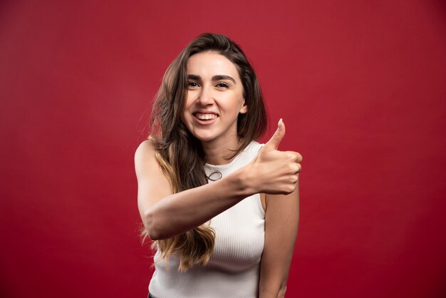 Young pretty brunette woman model showing a thumb up 