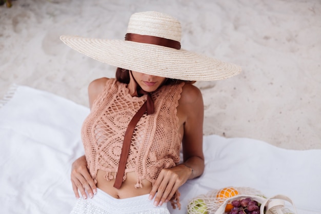 Free photo young pretty caucasian tanned fit woman in knitted clothes and hat on beach