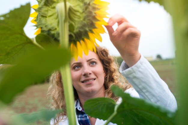 Young pretty expert agronomist in the sunflower field checking crops quality