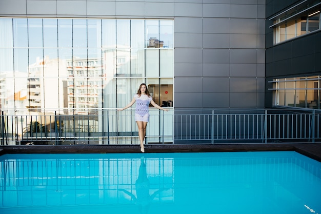 Young pretty fashion sport woman posing outdoor in summer in hot weather in bikini on pool