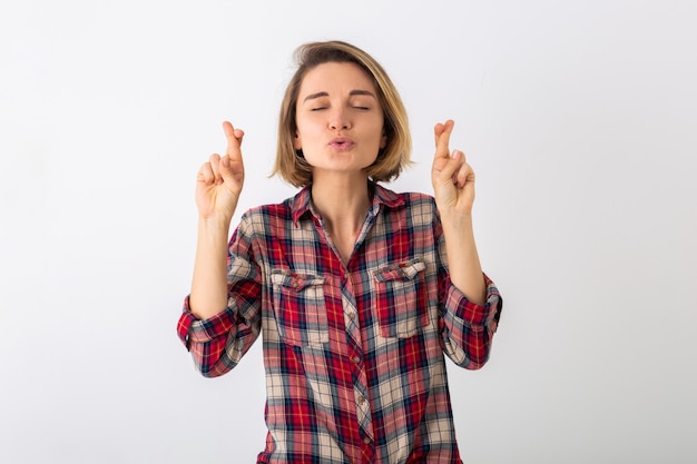 Young pretty funny emotional woman in checkered shirt posing isolated on white studio wall, showing lucky gesture