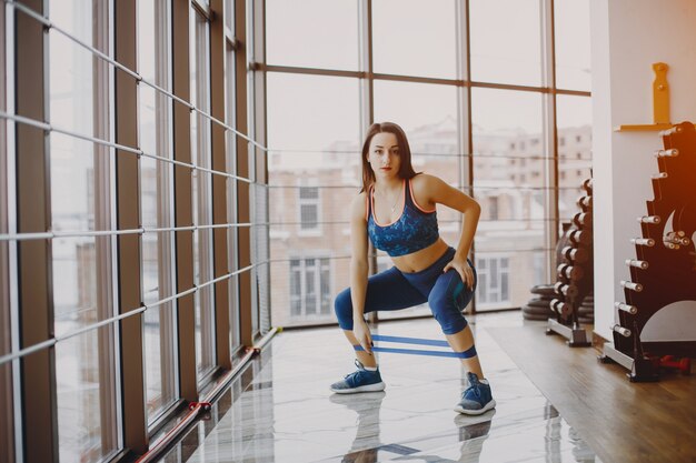 young and pretty girl in a blue sports suit is engaged in sports in the gym