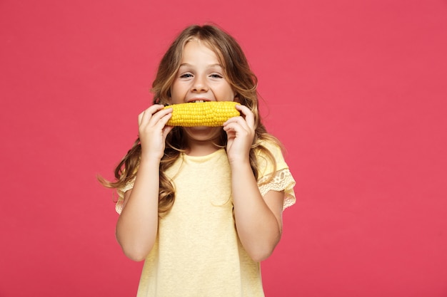 Free Photo young pretty girl eating corn over pink wall