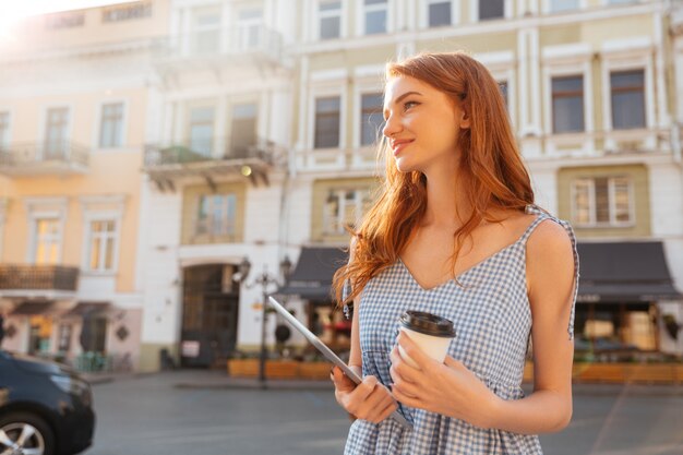 Young pretty girl holding pc tablet and cup of coffee