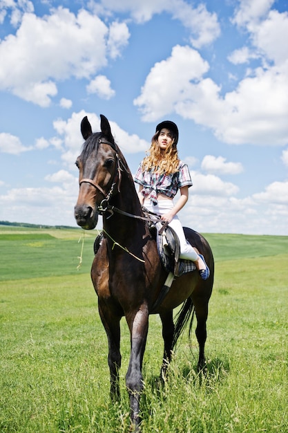 Free photo young pretty girl riding a horse on a field at sunny day