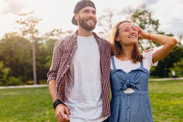 Young pretty hipster couple walking in park, friends having fun together, romance on date, summer fashion style, colorful hipster outfit, man and woman smiling embracing