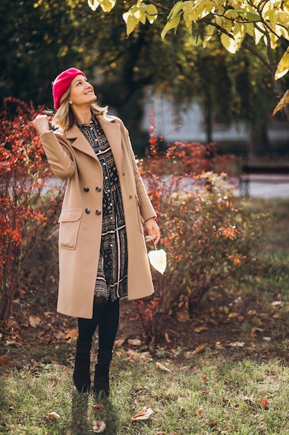 Free Photo young pretty lady in a red barret outside in park