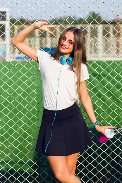 Free photo young pretty lovely hipster woman posing with cup of healthy juice, listening favorite music