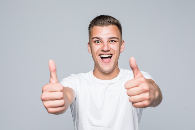 Young pretty man in a white T-shirt isolated on white hold thumbs up