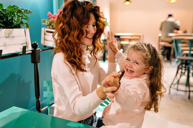 Young pretty red-haired mother with her little adorable curly child spend weekend in family