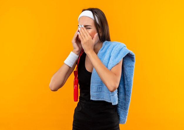 Young pretty sporty girl wearing headband and wristband with towel on shoulder