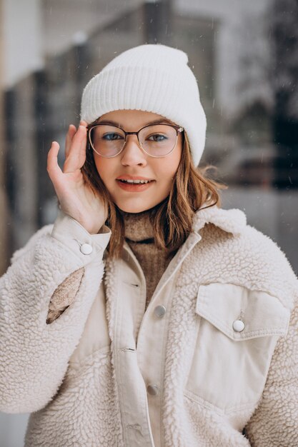 Young pretty woman in beige outfit walking in the street at winter time