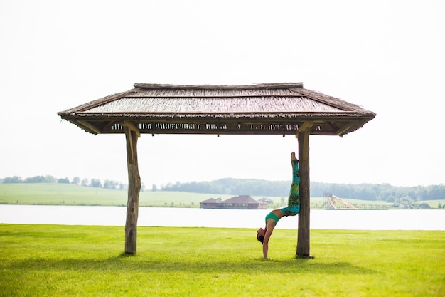 Free photo young pretty woman doing yoga in morning park near lake