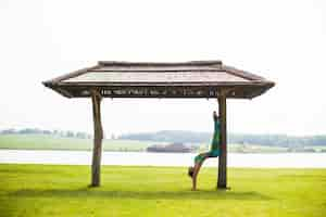 Free photo young pretty woman doing yoga in morning park near lake