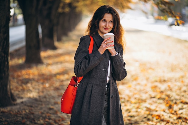 Young pretty woman drinking coffee in park