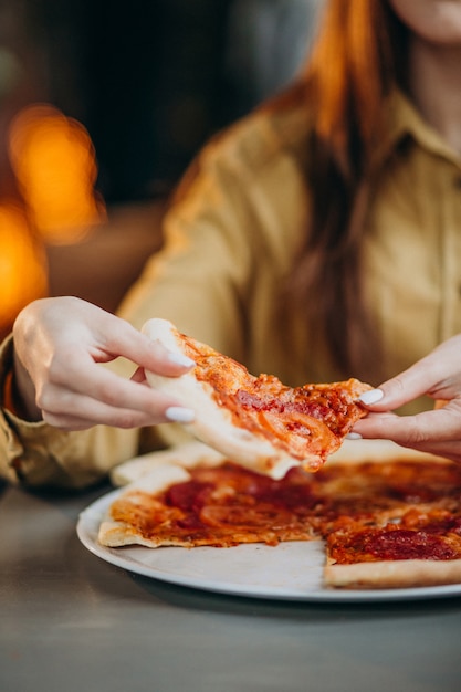 Free photo young pretty woman eating pizza at a bar