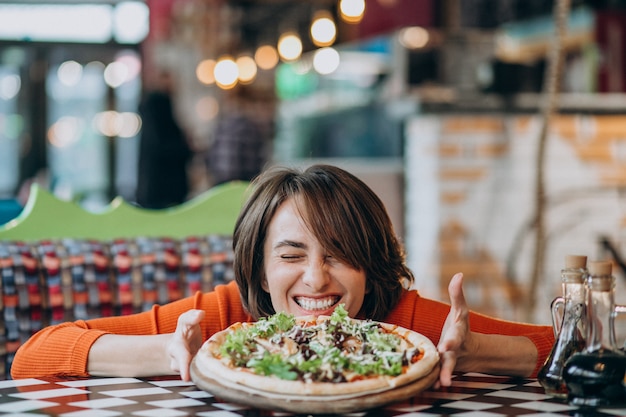 Young pretty woman eating pizza at pizza bar