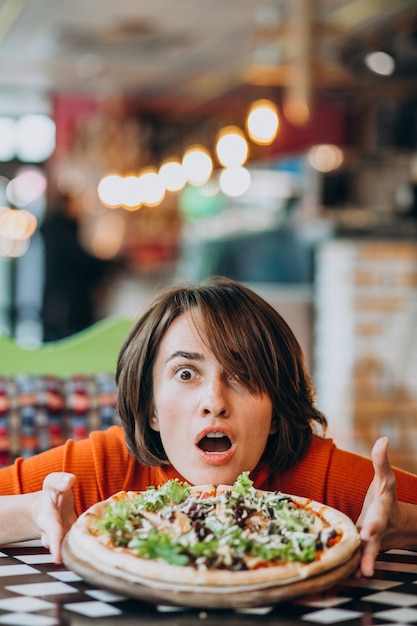 Free photo young pretty woman eating pizza at pizza bar