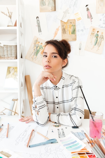 Free photo young pretty woman fashion designer sitting at her work desk