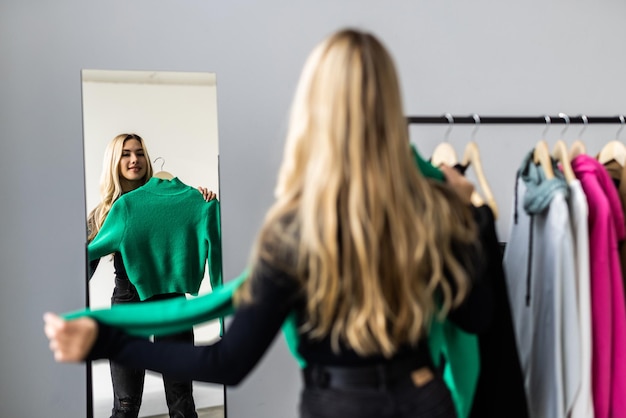 Free photo young pretty woman looking into mirror near wardrobe at home