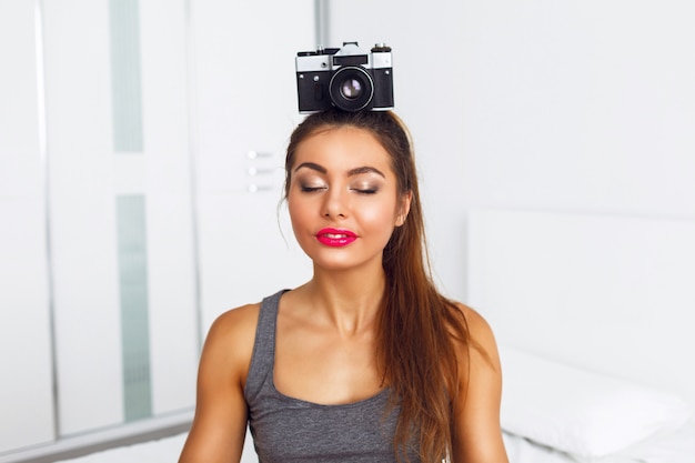 Young pretty woman meditate with vintage camera on her head