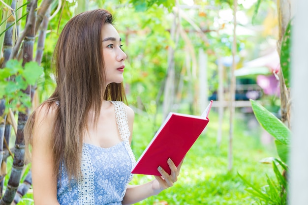 Young pretty woman reading book in park