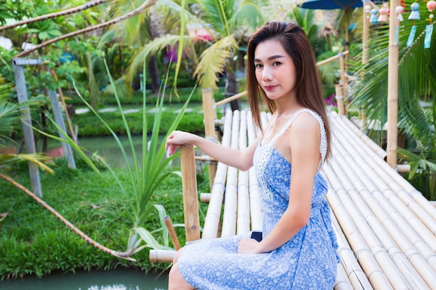 Young pretty woman sitting on bamboo bridge in garden