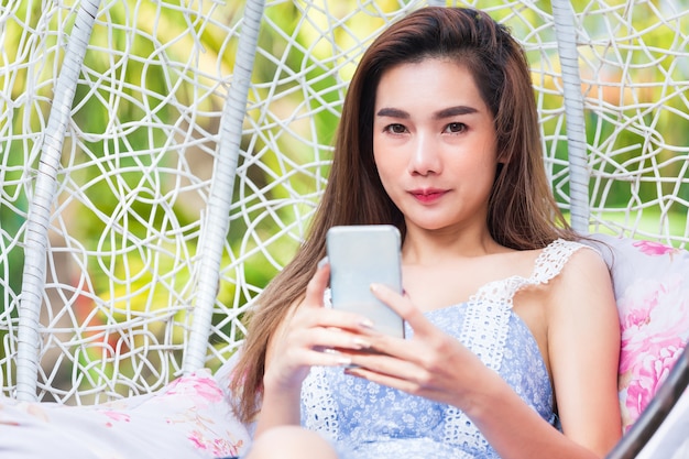 Young pretty woman using smartphone in swing