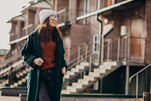 Free photo young pretty woman in warm coat by the house