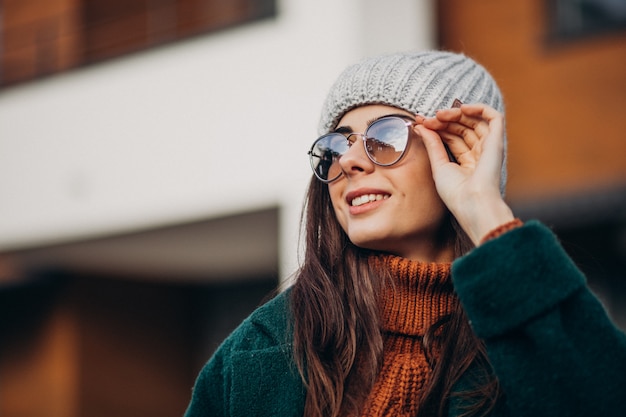 Young pretty woman in warm coat by the house