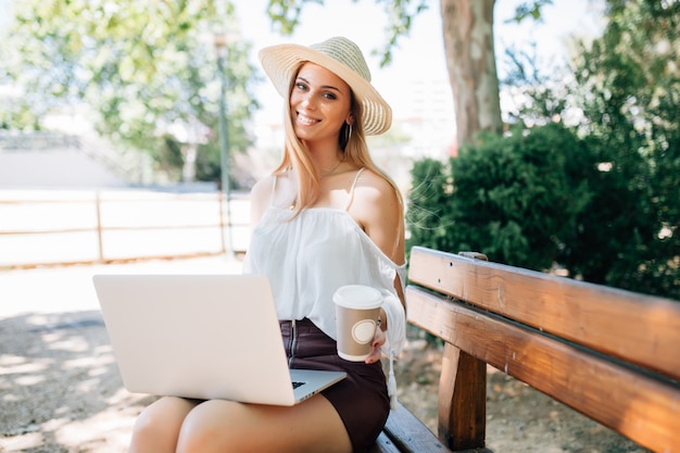 Young pretty woman with a laptop on a park bench